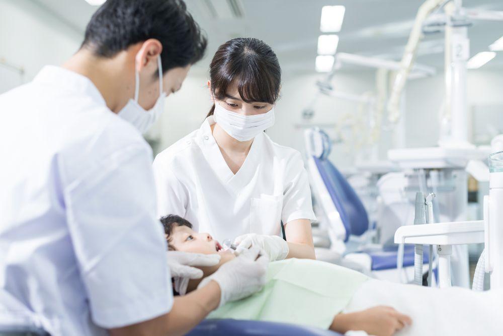 歯医者で治療する歯科医と助手